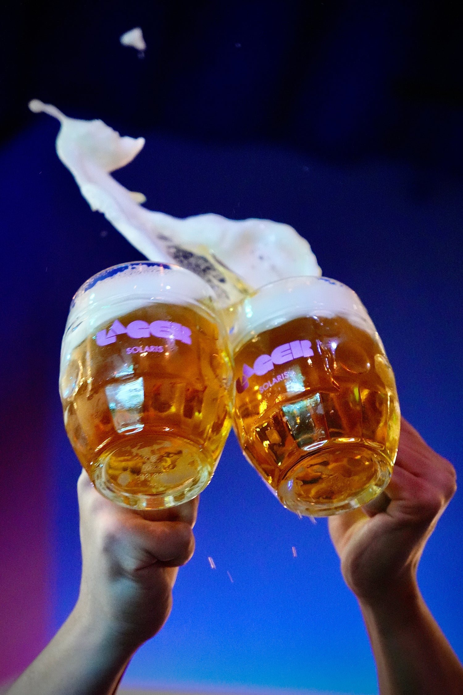 Two lagers in mugs being knocked together in celebration